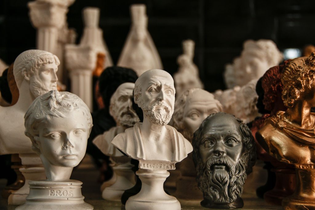 Obras de arte antiguas con bustos y figuras decorativas dispuestas sobre una mesa.